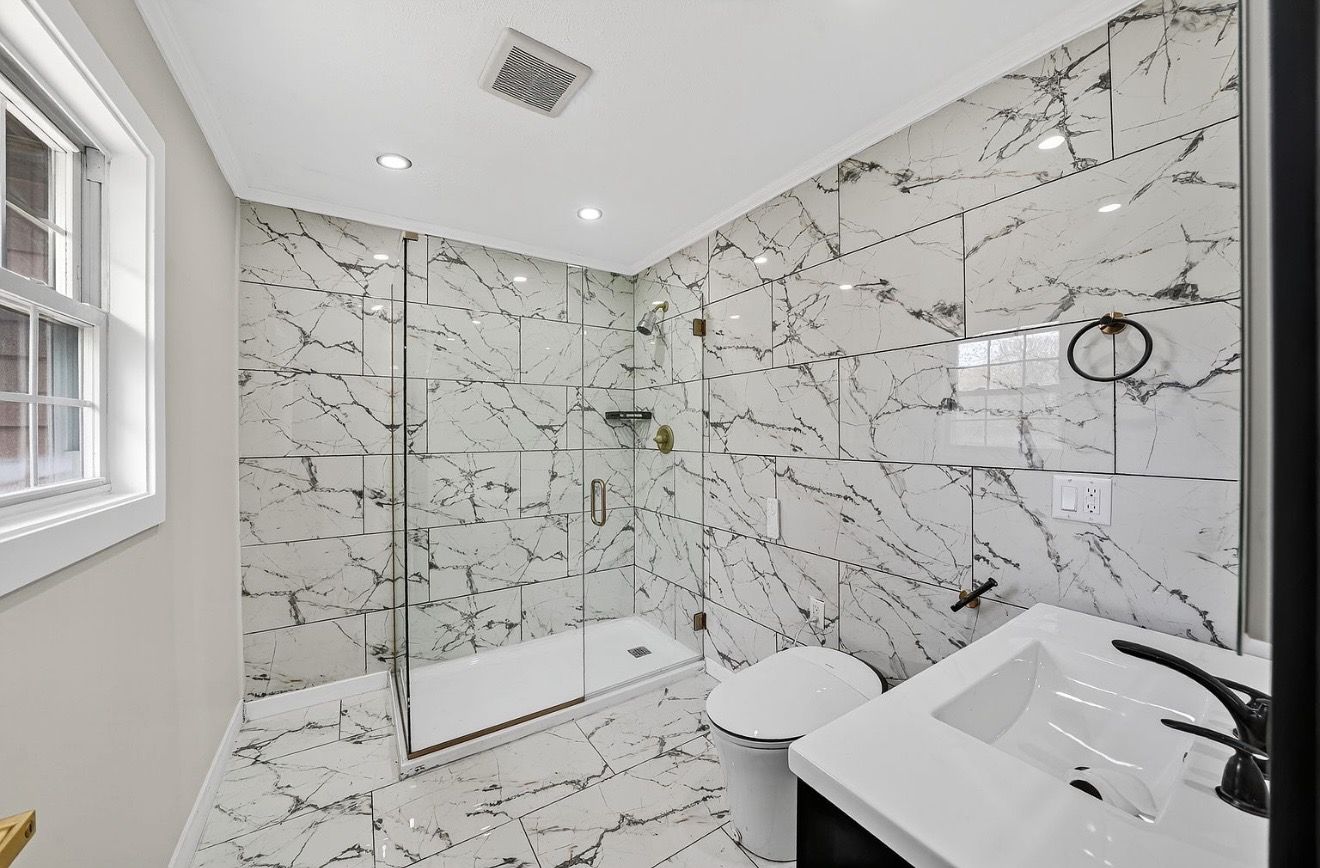 Completed bathroom remodel with marble-look tile and a glass walk-in shower